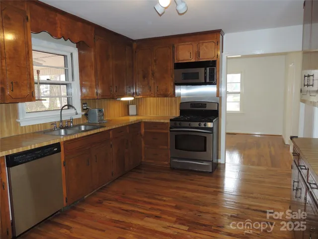 a kitchen with wooden floors and stainless steel appliances