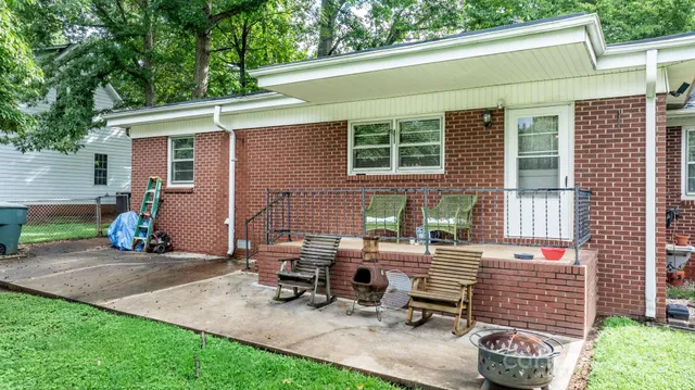 a view of a backyard with chairs and a table under an umbrella