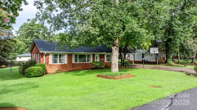 a front view of a house with a garden and trees
