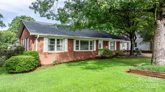 a front view of a house with a garden and trees