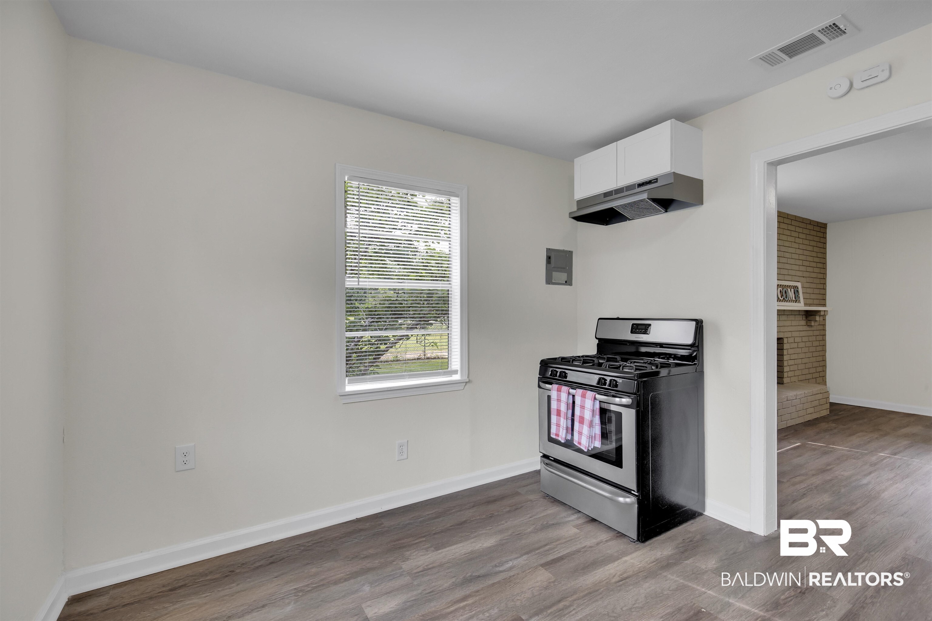 9241 Vallaris Street North Mobile, AL 36608 - Photo 14 of 17 Kitchen featuring white cabinets, stainless steel range with gas stovetop, visible vents, wood finished floors, and under cabinet range hood