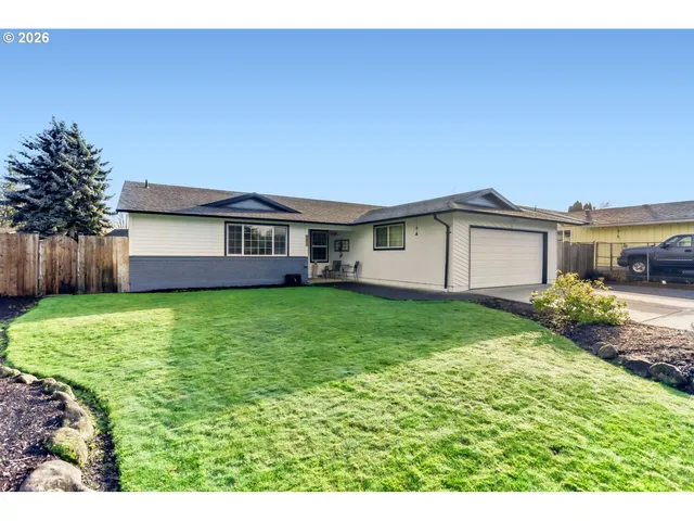 a view of a house with a yard and a large tree