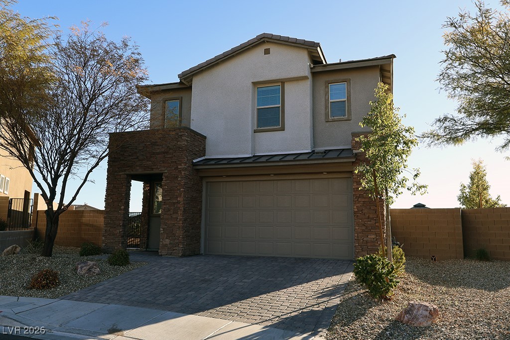 Traditional-style house featuring an attached garage, stone siding, a standing seam roof, driveway, and stucco siding