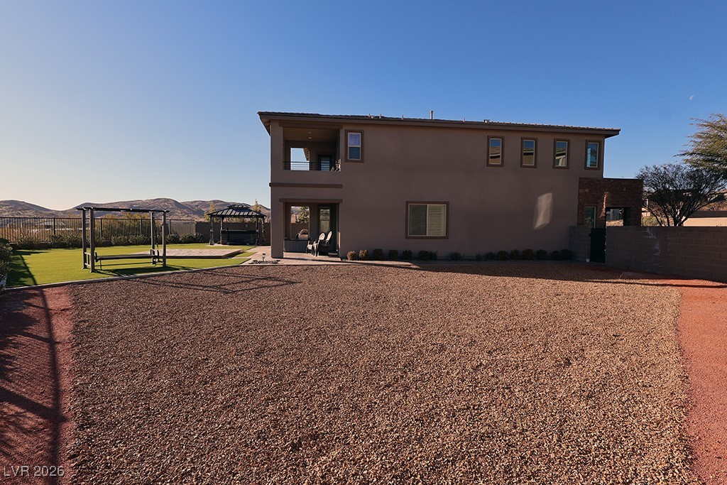 764 Rogue Wave Street Las Vegas, NV 89138 - Photo 32 of 36 Back of property featuring a mountain view, stucco siding, a balcony, and a patio