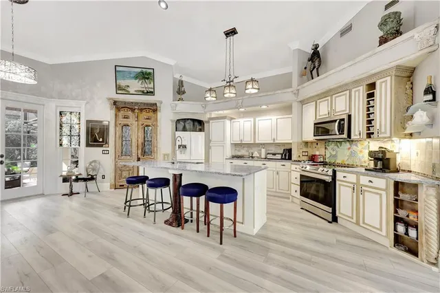 a kitchen with stainless steel appliances granite countertop a stove top oven a sink a dining table and chairs with wooden floor