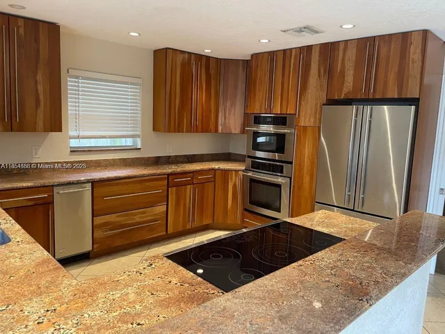 a kitchen with stainless steel appliances granite countertop a refrigerator and a sink
