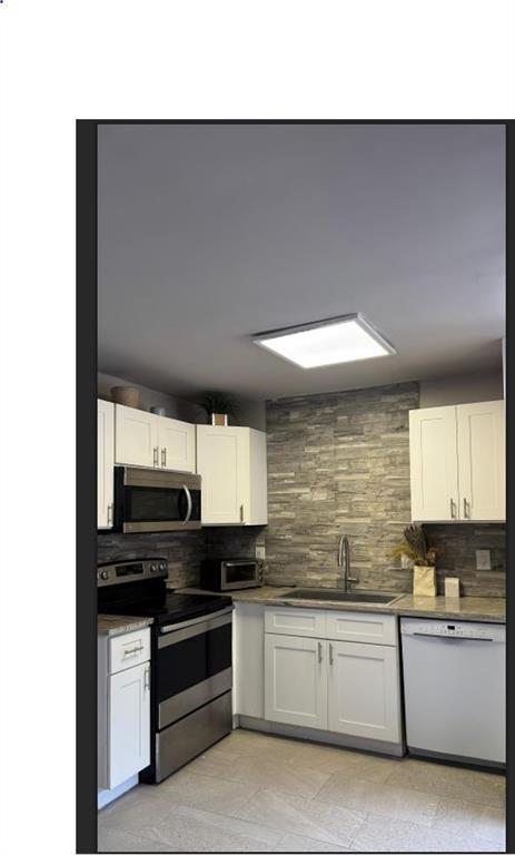 8110 Skillman Street, Unit 2057 Dallas, TX 75231 - Photo 15 of 16 Kitchen featuring stainless steel appliances, tasteful backsplash, white cabinetry, and dark stone countertops