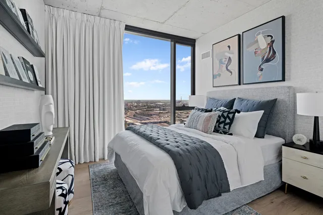 a bedroom with a bed painting on wall and a large window