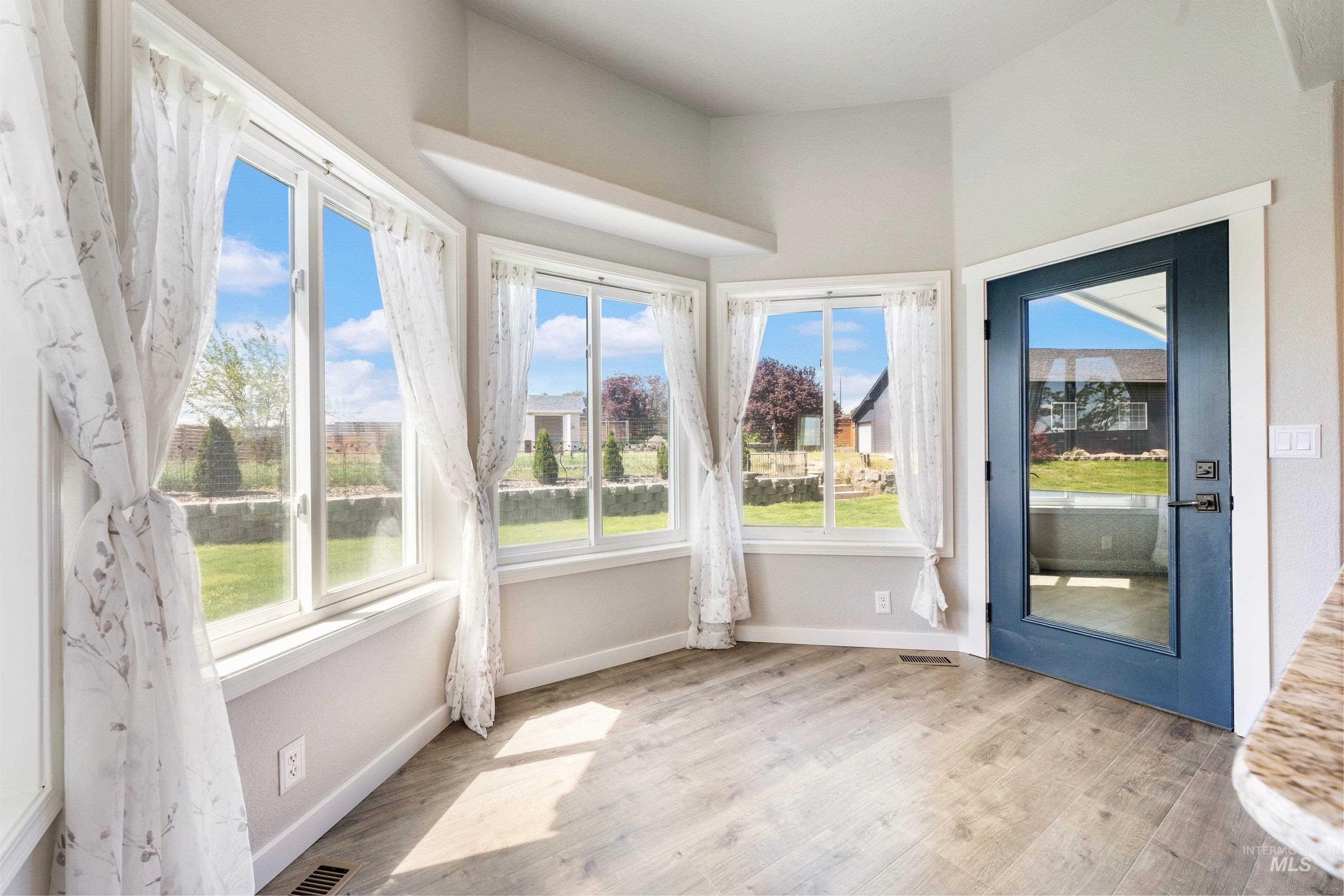 7657 Track Road Nampa, ID 83686 - Photo 16 of 49 Room featuring multiple windows, wood-finish flooring, and a blue full-light door