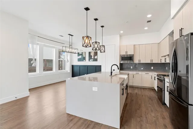 a large kitchen with kitchen island a large counter top space a sink stainless steel appliances and cabinets