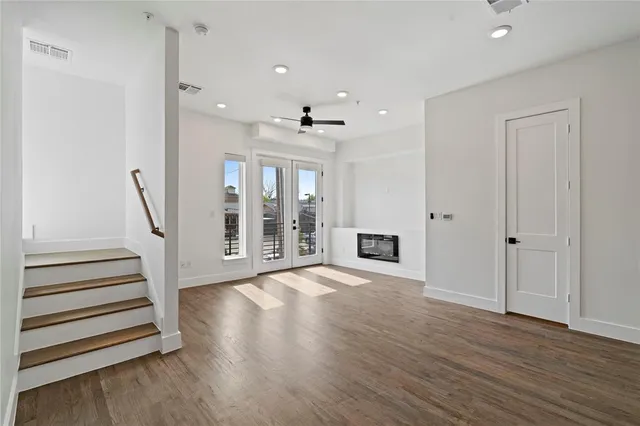 a view of an empty room with wooden floor and a ceiling fan