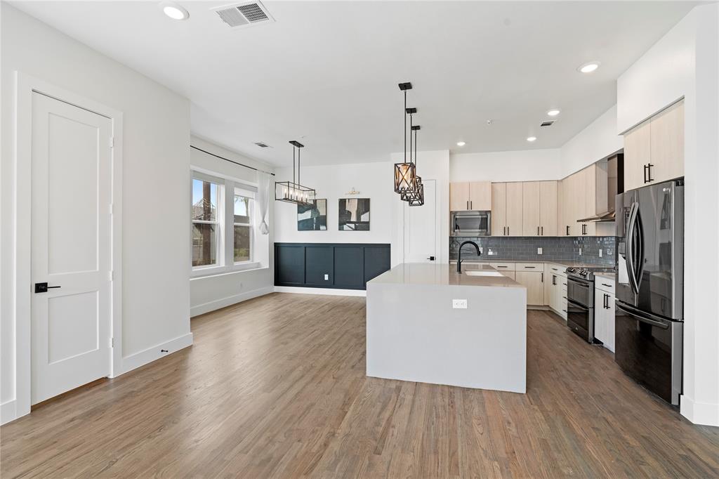 1804 Ripley Street, Unit 105 Dallas, TX 75204 - Photo 8 of 25 a large kitchen with cabinets wooden floor and stainless steel appliances