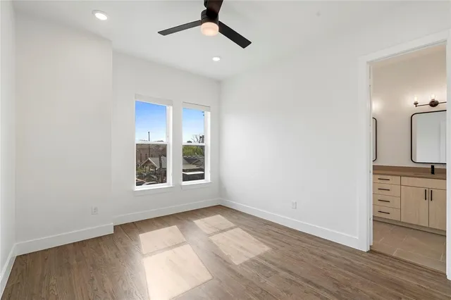 an empty room with wooden floor cabinet and windows