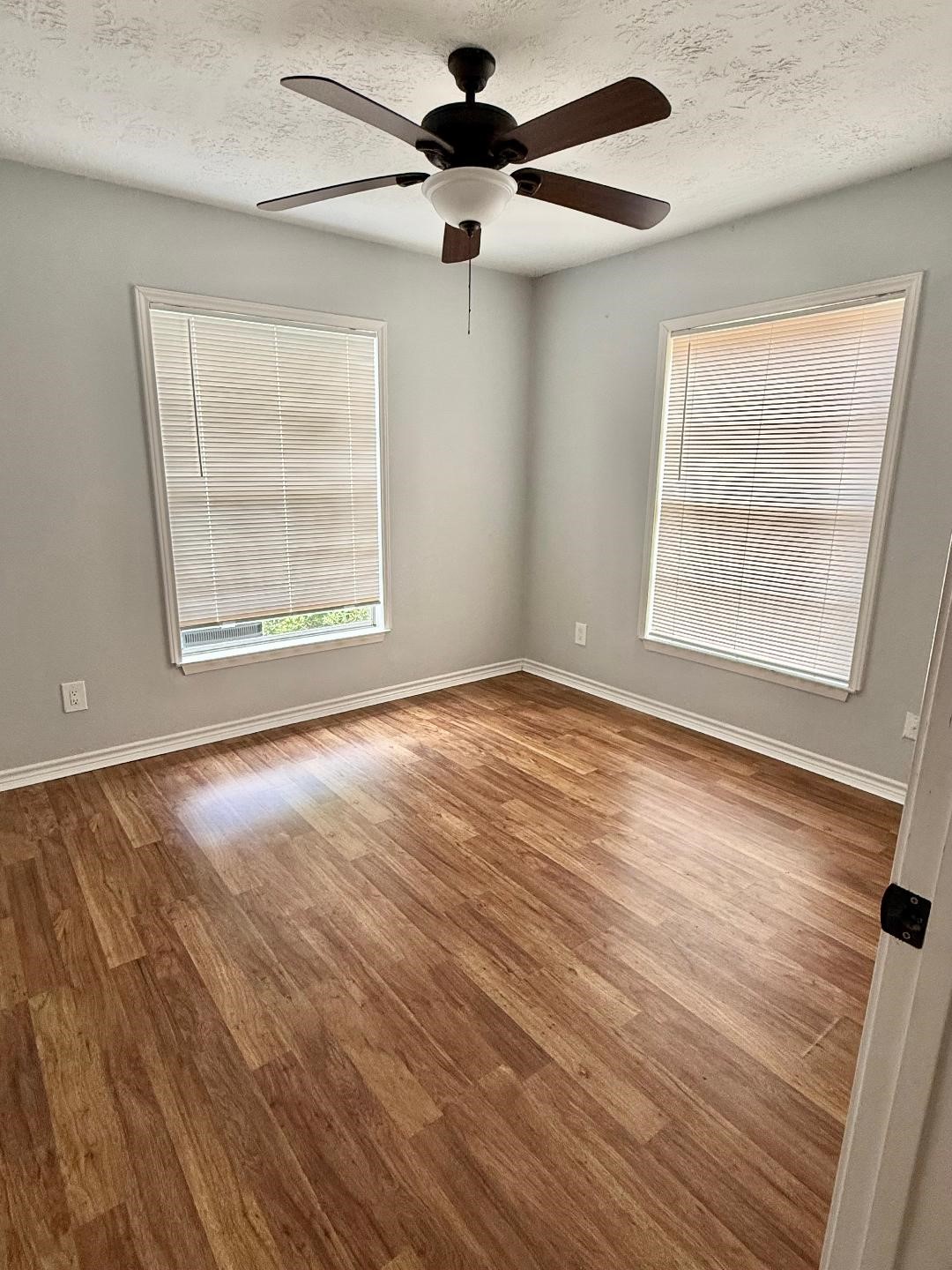 306 Rustic Drive Pasadena, TX 77502 - Photo 17 of 28 an empty room with wooden floor chandelier fan and windows