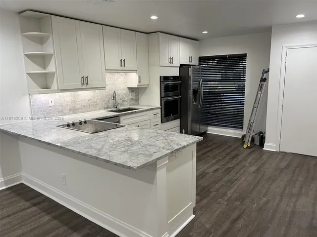 a kitchen with stainless steel appliances granite countertop a sink refrigerator and cabinets