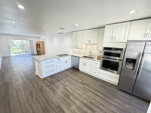 a kitchen with stainless steel appliances a stove top oven a sink and a refrigerator