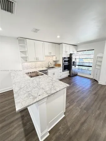 a kitchen with stainless steel appliances granite countertop a stove a sink and white cabinets