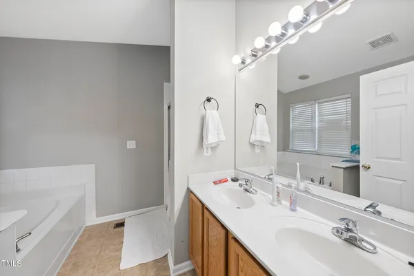 a bathroom with a double vanity sink a mirror and a bathtub
