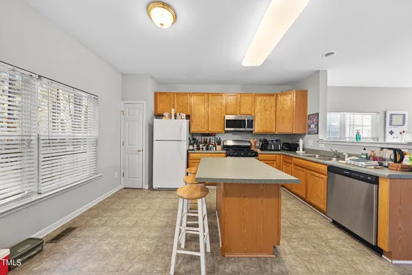 a kitchen with stainless steel appliances granite countertop a stove top oven a sink a dining table and chairs