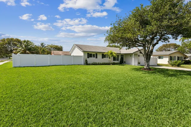 a view of a house with a big yard and large trees