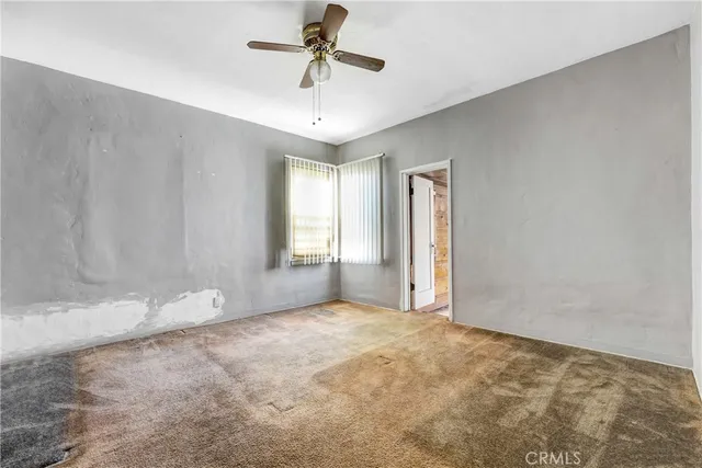 an empty room with windows and fan chandelier