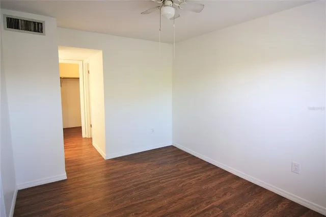 a view of a room with wooden floor and a ceiling fan