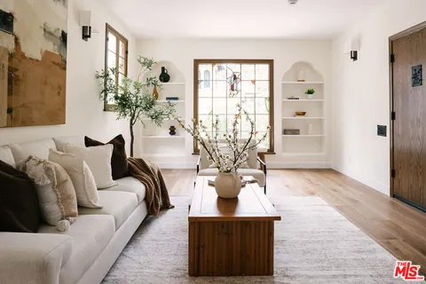 a living room with furniture a potted plant and a large window