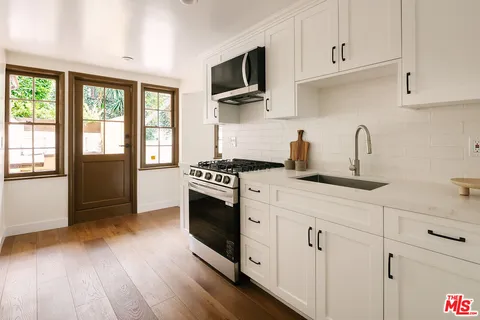 a kitchen with stainless steel appliances white cabinets a sink and a stove