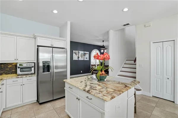 a kitchen with stainless steel appliances kitchen island granite countertop a refrigerator and a sink
