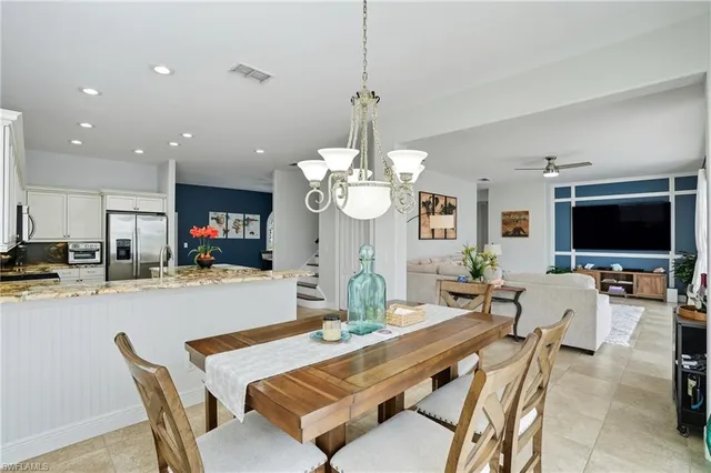 a dining room with wooden floor a chandelier a wooden table and chairs