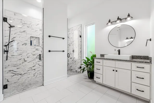 a bathroom with a granite countertop sink a mirror a vanity and a shower