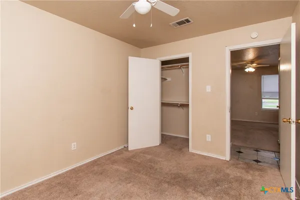 an empty room with closet and a chandelier fan