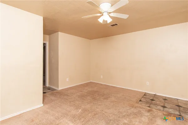 an empty room with a ceiling fan and a window