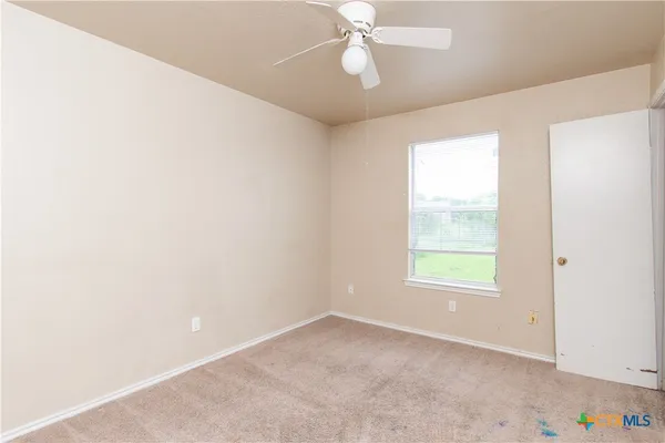 an empty room with a window and ceiling fan