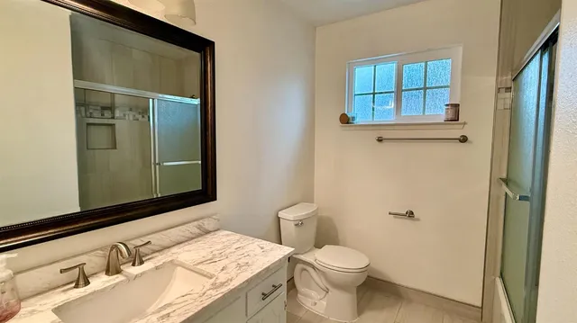 a bathroom with a granite countertop sink toilet and shower