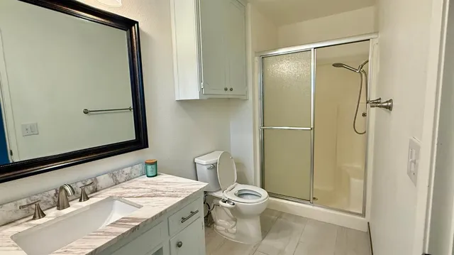 a bathroom with a granite countertop sink toilet and shower