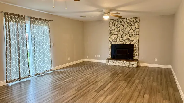 wooden floor in an empty room with a fireplace and wooden floor