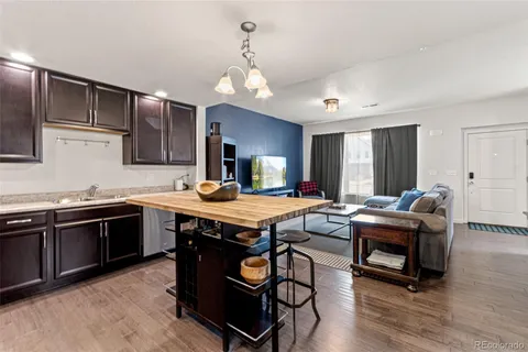 a kitchen with stainless steel appliances granite countertop a stove a sink dishwasher and a refrigerator with wooden floor