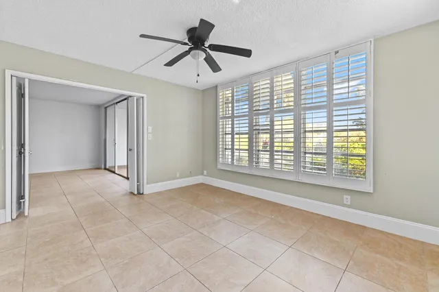 an empty room with wooden floor ceiling fan and windows