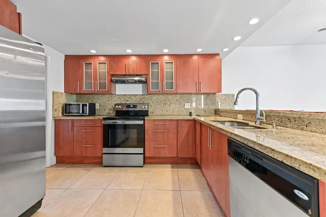 a kitchen with stainless steel appliances granite countertop a stove a sink and a microwave