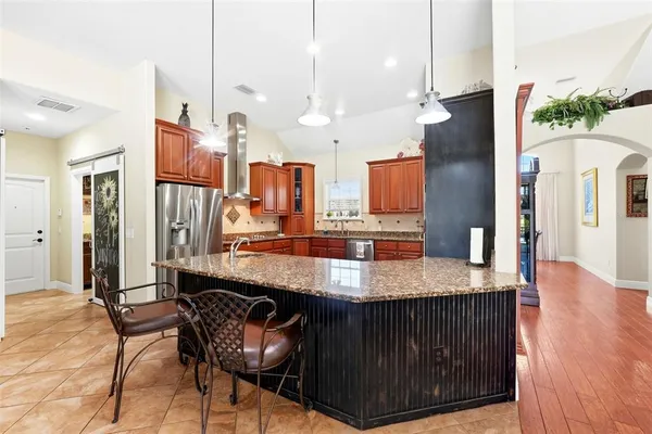 a kitchen with stainless steel appliances granite countertop a sink refrigerator and cabinets