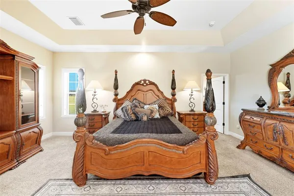 a bedroom with a large bed a flat tv screen and a dresser