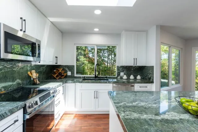 a kitchen with stainless steel appliances granite countertop a sink a stove a refrigerator a microwave a counter top space and cabinets