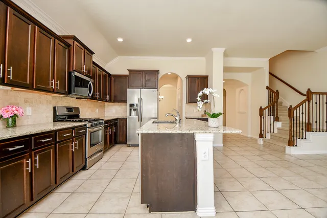 a large kitchen with stainless steel appliances wooden cabinets and a stove top oven