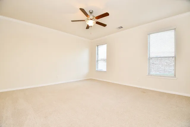 an empty room with ceiling fan and windows