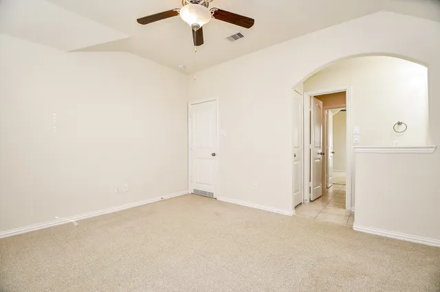 an empty room with a ceiling fan and a window