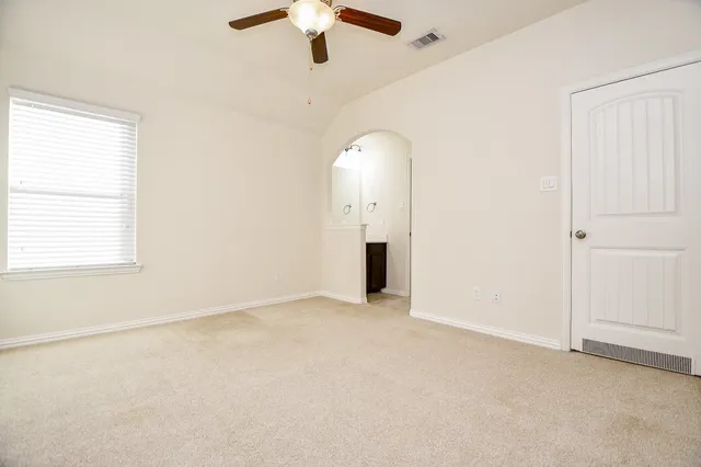 an empty room with a chandelier fan and windows
