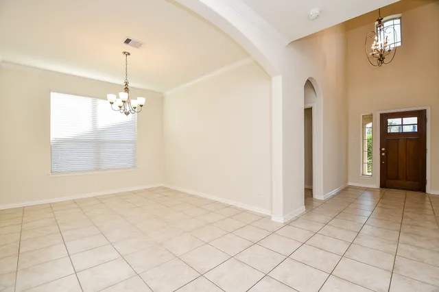 a view of an empty room with window and chandelier fan
