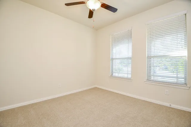 an empty room with a window and a ceiling fan