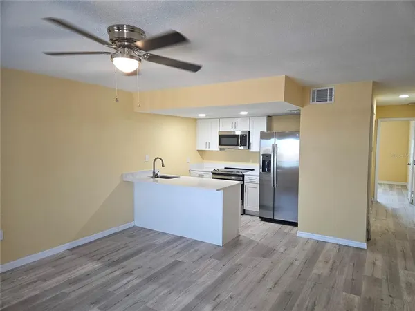 a view of kitchen with stainless steel appliances wooden floor and window